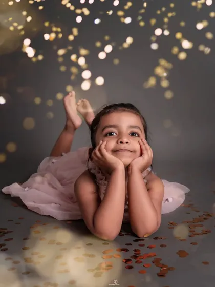 Daydreaming in a shower of sparkles. This sweet, thoughtful pose captures a different side of this little girl's personality during her magical portrait session.