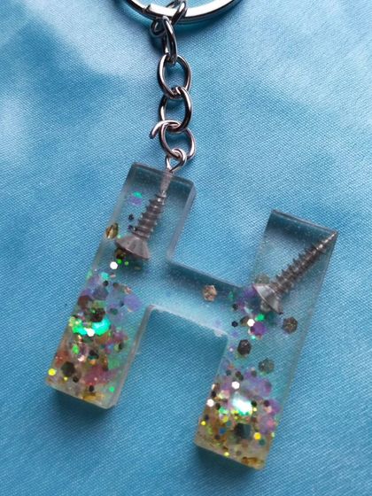 A fun and quirky keychain I made for a dad. This 'H' initial keychain has real screws and multicolor glitter embedded inside, making it a unique and humorous gift for the handyman in your life.