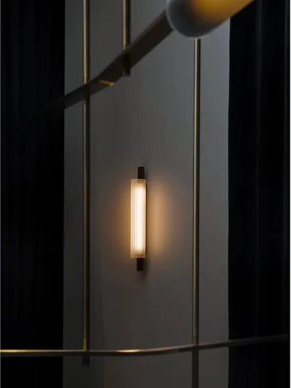 A Volant wall sconce provides accent lighting in a hallway, demonstrating the collection's ability to create a cohesive lighting scheme throughout a project.