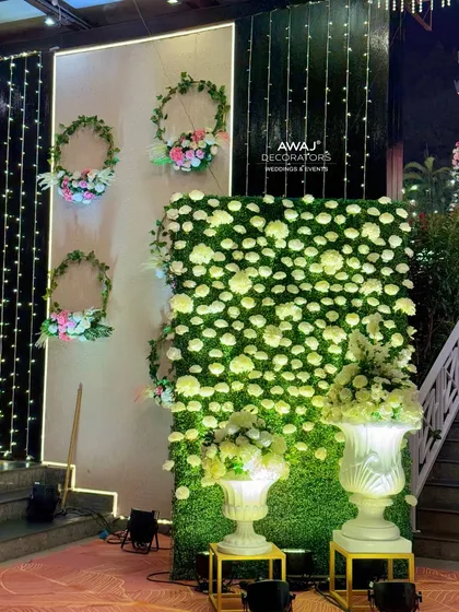 A detail of the entrance decor, with a wall of white flowers and greenery, and elegant floral arrangements in large white urns.