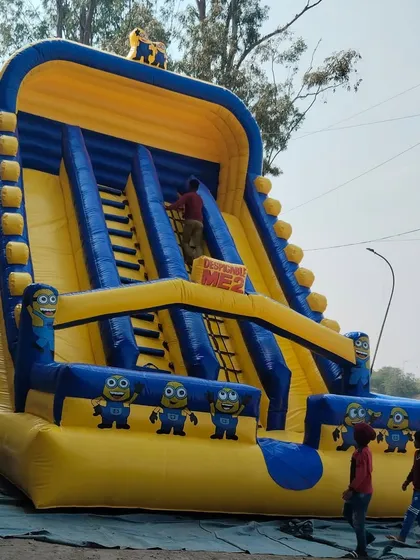 Dekhiye, this is our giant Minions-themed inflatable slide. It has two sliding lanes and two climbing ladders in the middle. Kids love the bright yellow and blue colors and seeing their favorite characters.