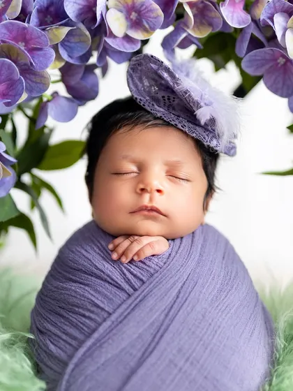 A detailed close up of a sleeping newborn's face, framed by purple flowers and wearing a delicate little hat. These shots are perfect for capturing those tiny features you never want to forget.