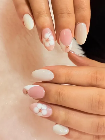 A simple and elegant floral design. This set features a mix of solid white and pink nails with delicate, hand-painted white flowers accented with a tiny rose gold bead.
