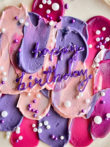 A close-up of my abstract buttercream art. I use a palette knife to create textured strokes in shades of pink, purple, and fuchsia, topped with delicate sugar pearls for a modern, artistic birthday cake.