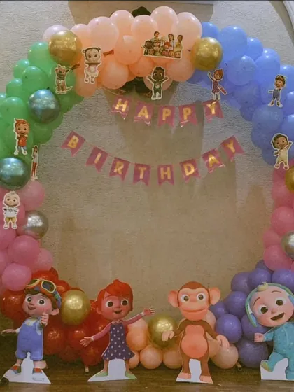 A Cocomelon themed ring backdrop decorated with pastel balloons and cutouts of JJ and his friends, perfect for a birthday photo booth.