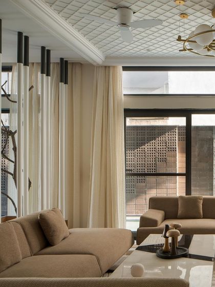 The living room's design is a study in contrasts, with a textured brick wall, a gridded ceiling, and soft, neutral-toned furniture. The space is both rugged and refined.