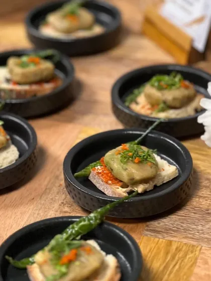 A Mumbai-style open sourdough toast. This appetizer features a savory topping with a hint of dry garlic chutney, served on a crisp slice of sourdough bread.