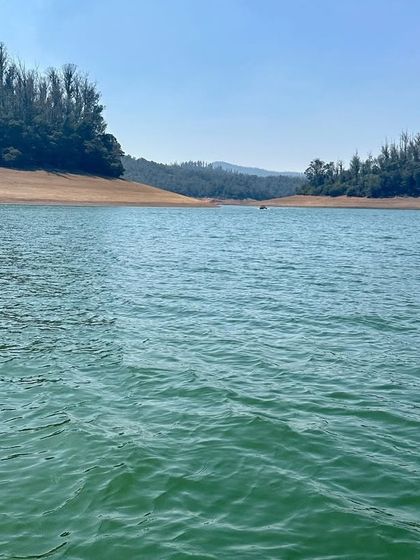 The clear, turquoise waters of Pykara Lake in Ooty on a bright sunny day. A perfect spot for nature lovers.