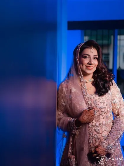 A lovely shot against a cool blue background. The contrast makes her soft pink outfit and glowing makeup pop, showcasing her beautiful smile.
