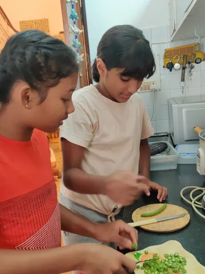 Two older girls collaborate in the kitchen, preparing a nutritious meal for the street dogs who visit our school. This act of service combines practical cooking skills with empathy and care for our community animals.