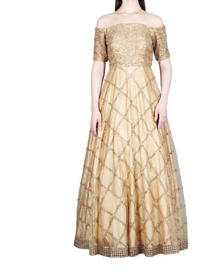 Our AARNA label offers timeless elegance, like this off-shoulder gold gown. The intricate lattice beadwork on the skirt and the fitted bodice create a classic ballroom silhouette, making it an exquisite choice for a formal reception or black-tie event.