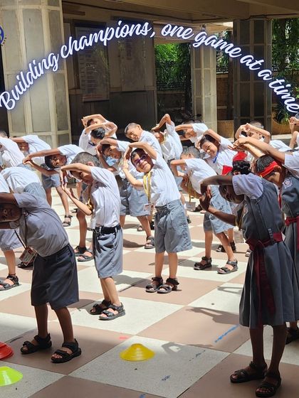 "Building champions, one game at a time." Young students are seen here doing stretching exercises together, an essential part of every sports session to improve flexibility and prevent injury.