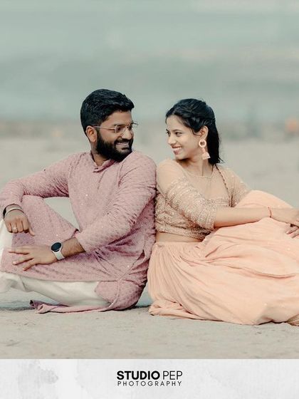 A relaxed and happy portrait of the couple sitting back-to-back on the sandy banks of the Yamuna. Their easy smiles and comfortable pose reflect their deep bond.