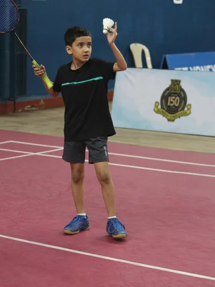 The focus and determination of a young athlete preparing to serve during a competitive match. We create a professional tournament environment where junior players can test their skills and grow.