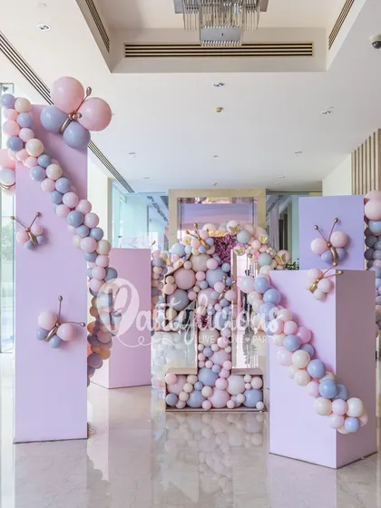 An elegant entrance to a butterfly-themed party. We used large, pastel-colored columns and cascading balloon garlands to create a grand and sophisticated entryway for guests.