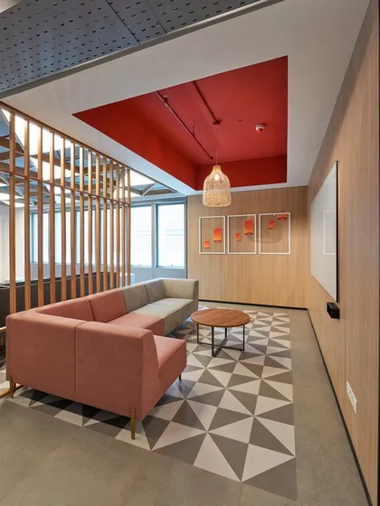 A semi-enclosed lounge space with a pink sofa and a geometric-patterned floor. The red ceiling adds a bold, unexpected design element.