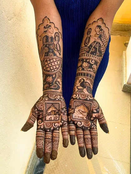 This is a classic Indian bridal henna design featuring traditional figures. On one arm, a woman holds a mirror, and on the other, a woman plays a dholak drum. These timeless motifs, combined with peacocks and lotus flowers, celebrate our rich culture.