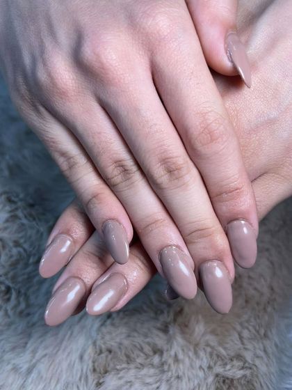 A simple, glossy nude polish on medium-length almond nails. Effortlessly chic.