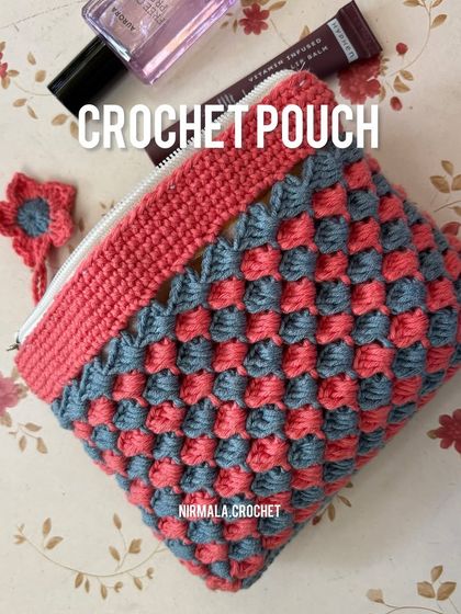 A flat lay of the pink and grey pouch, showing off the beautiful stitch pattern and the cute flower zipper pull.