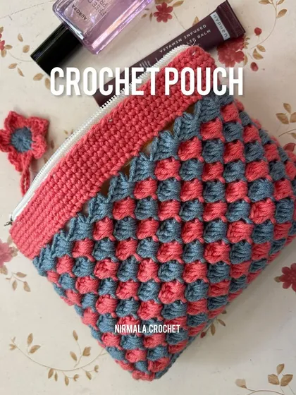 A flat-lay view of our pink and grey crochet pouch, showing off the beautiful texture and color combination. It's perfect for holding makeup, as shown here.