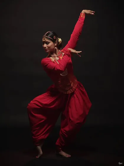 This image captures the fluidity and grace of the dancer's movement. The composition and lighting work together to create a timeless portrait of a traditional artist in her element.