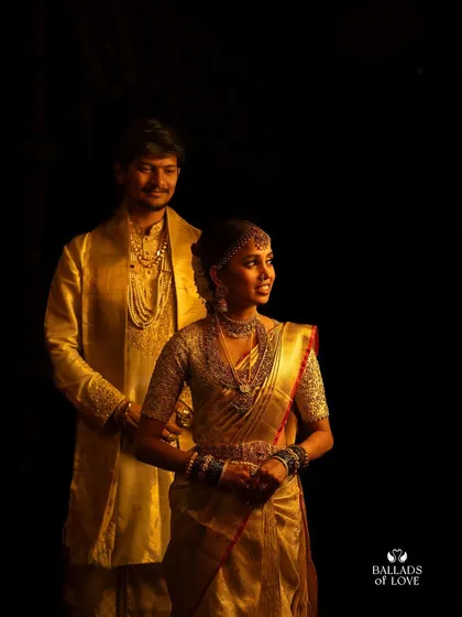 A duplicate of image 93, a classic portrait of a bride and groom. The bride's fully embroidered blouse shines against her traditional gold silk saree.