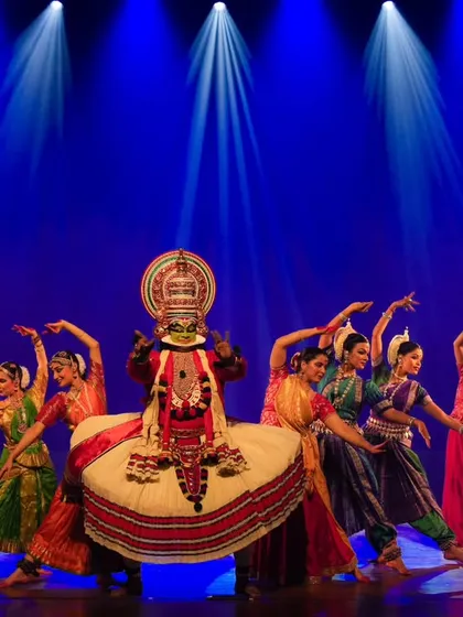My troupe, Trikayaa Dance Foundation, performing in 'Colours of India'. The stage is lit to create a dramatic atmosphere, highlighting a central Kathakali artist surrounded by a vibrant ensemble.