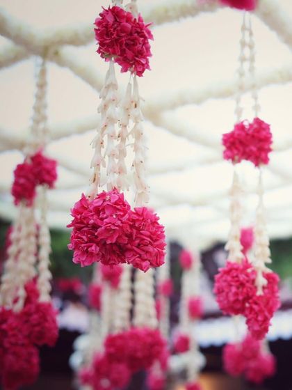 Delicate hanging floral arrangements of pink carnations and white tuberose, adding a fragrant and beautiful detail to the wedding decor.