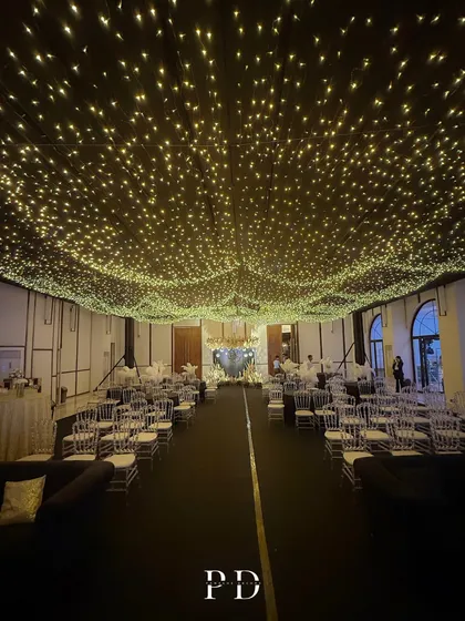 The view down the aisle of the 'Night Under The Stars' Sangeet. The fairy light canopy extends across the entire hall, creating a breathtaking and cohesive design.