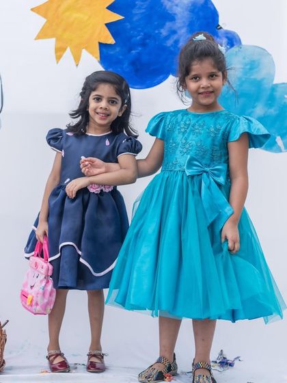 Two sisters, one in navy and one in turquoise. While the colors are different, the similar style with puff sleeves and a full skirt creates a lovely, coordinated look.
