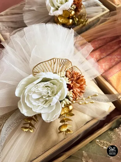A different color palette for trousseau styling, featuring a large white peony and warm-toned flowers against white tulle. Every design is customized to the client's wedding theme.