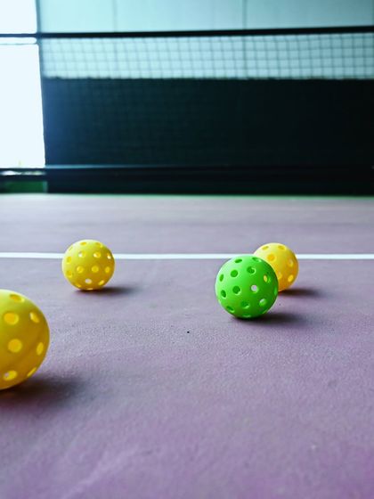 A close-up of pickleballs on our purple court. These lightweight, perforated balls are what make the game so unique.