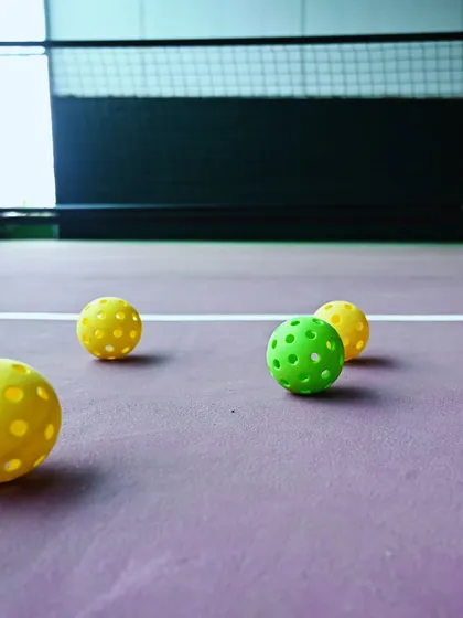 A close-up of colorful pickleballs scattered on the purple court. This artistic shot captures the readiness and fun spirit of the game at my facility.