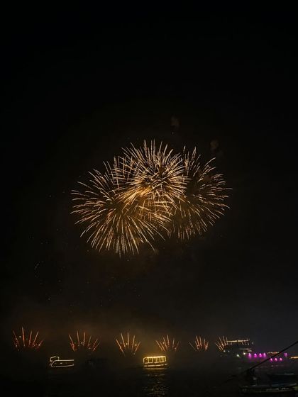 Fireworks exploding over the Ganga river during Dev Deepawali. This captures the peak moment of celebration against the dark night sky.