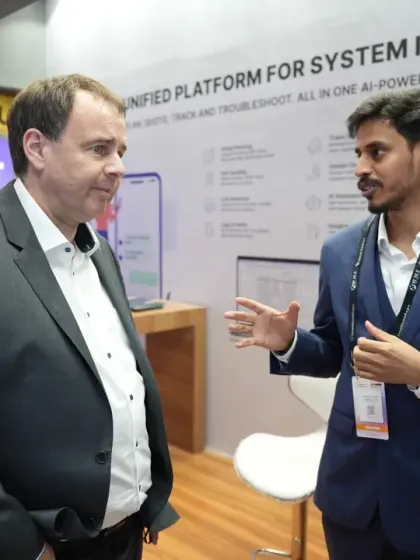 A focused conversation between an exhibitor and an international delegate in front of a booth detailing a unified platform for system integrators. This highlights the B2B focus of our event.