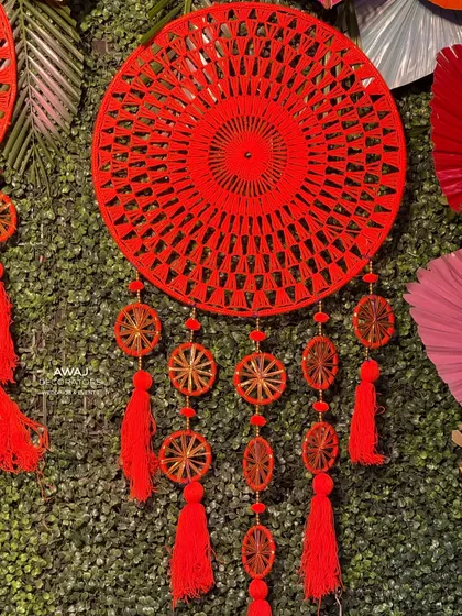 A close-up of a hand-woven red dreamcatcher, a beautiful and bohemian detail for a Mehendi party.