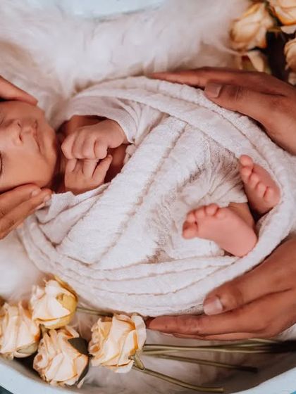 Held safely in loving hands. This shot symbolizes the protection and care surrounding a new baby. The delicate roses add a touch of timeless beauty.