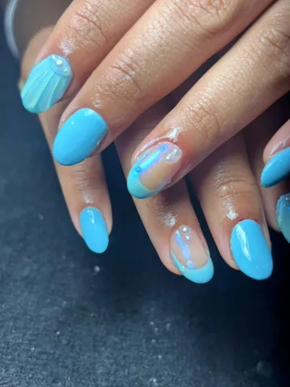 A fun, ocean-inspired design with bright blue polish, a 3D seashell, and encapsulated glitter for a "water" effect.
