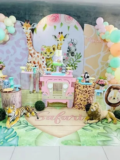 A full view of our pastel safari theme, perfect for a baby girl. The setup features a pink jeep-shaped dessert table, adorable animal characters with floral accents, and a custom printed floor mat.
