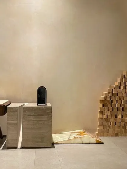 This minimalist composition in our office showcases our love for materials. The simple forms of the travertine and wooden pedestals are set against a smooth, lime-washed wall, creating a serene and sophisticated vignette.