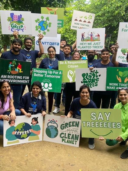 The NTT Data team celebrates a successful plantation drive at Aravali Creek, holding signs that say "Green City" and "Let's Plant A Forest Together."