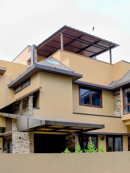 This perspective shows the layered composition of the building, with its multiple rooflines and the rooftop terrace, offering a blend of enclosed and open spaces.