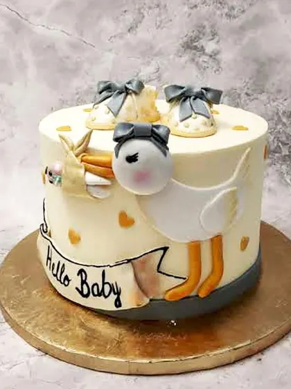 A charming "Hello Baby" cake featuring a stork delivering a precious bundle, with tiny baby shoes on top.