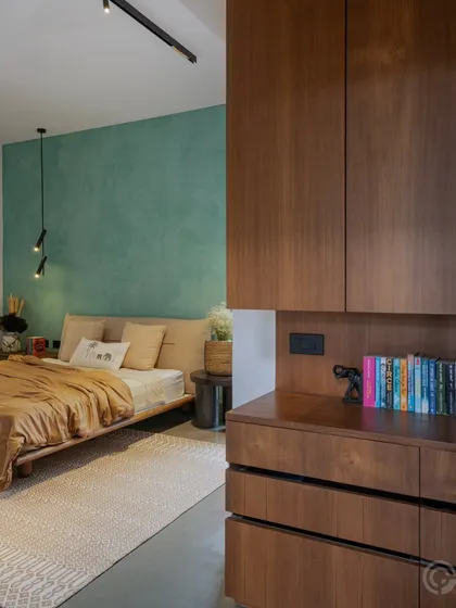 In this bedroom, a textured green accent wall provides a calm and earthy backdrop to the clean lines of the wooden bed and cabinetry. We balance bold color with natural materials to create private spaces that feel both refreshing and warm.