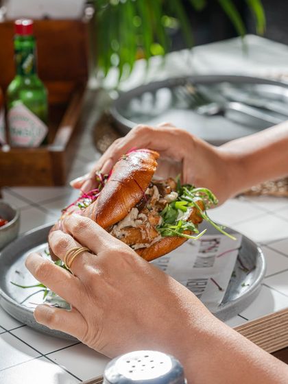 Hands holding one of our delicious bagel sandwiches, ready to be eaten. A perfect grab-and-go breakfast or lunch.