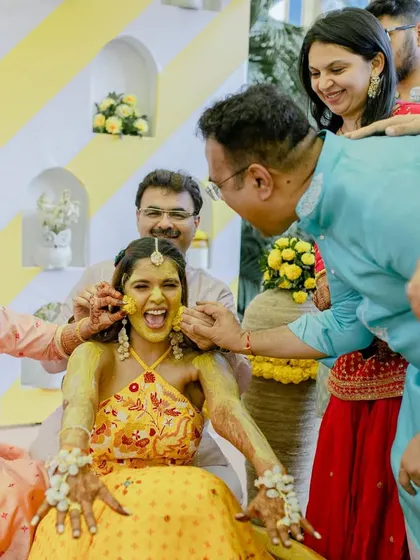 The bride's reaction as her family and friends lovingly apply haldi. A moment of pure, unadulterated fun.