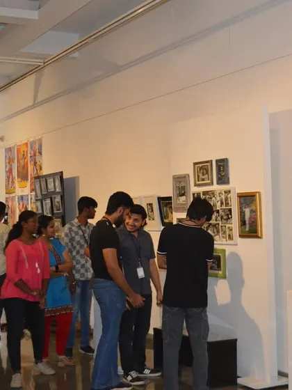 The students walking through the gallery, taking in the diverse collection of photographs and objects related to South Indian cinema.