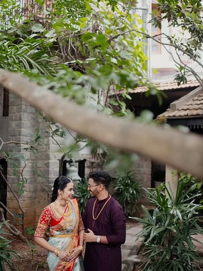 A couple framed by the foliage and the rustic stone buildings of the courtyard, a perfect blend of nature and architecture.