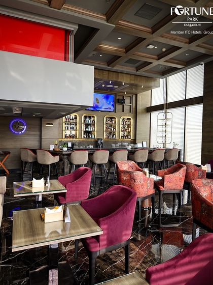 The full view of Neptune Bar & Lounge, showing the bar, high chairs, and comfortable lounge seating, all under a modern coffered ceiling.