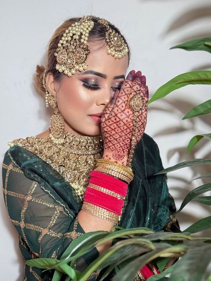A shy, coy pose from a bride in a green velvet outfit. The smokey eyes and heavy jewelry create a very traditional look.